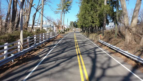 A low angle drone shot of a quiet country road on a sunny day. The camera dolly out over the double