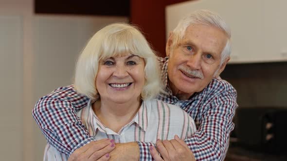 Senior Family Couple Hugging, Laughing, Smiling Looking at Camera During Coronavirus Lockdown