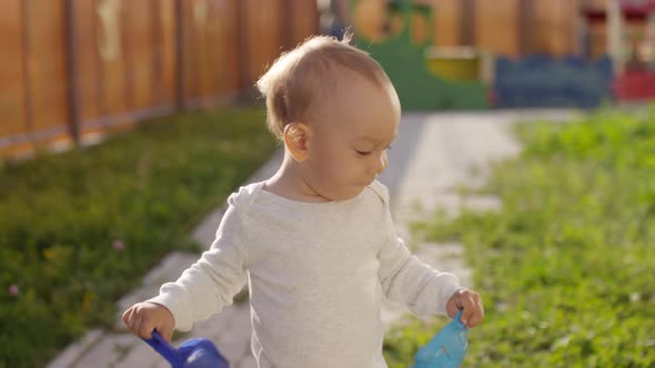 Toddler Walking with Sandbox Toys in Garden