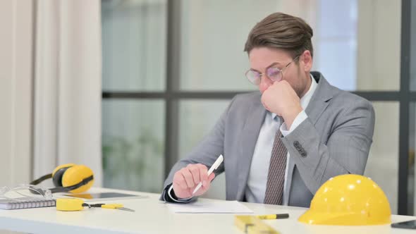 Middle Aged Engineer Thinking while Writing on Paper in Office