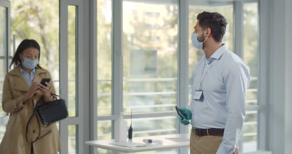 Modern Business Center Worker Scanning Visitors Vaccine Passport in Mobile Phone