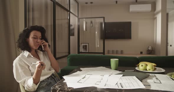 Woman Discussing Architectural Drafts During Phone Call