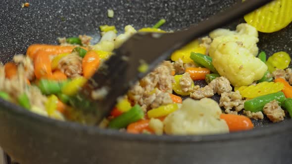 Close up view of steaming frying pan and mixed vegetables with frying minced.