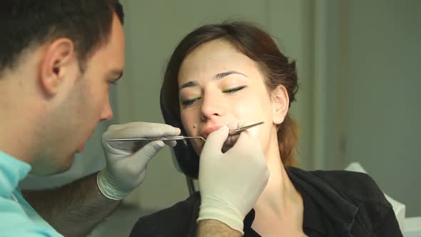 Female dentist showing dental instruments to a little girl