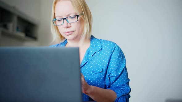 A Woman in Glasses Puts on Wireless Earphones and Starts an Online Meeting