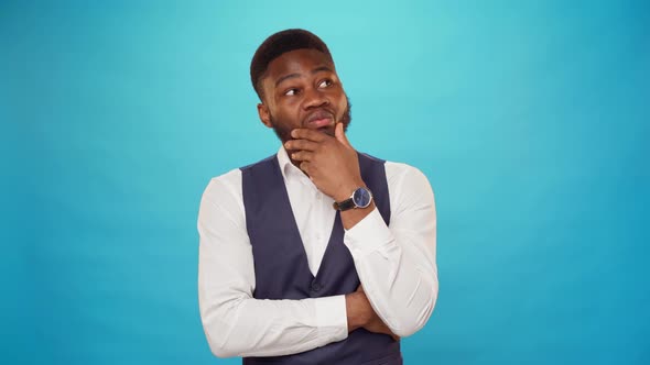 Young African American Man Thinking Against Blue Background