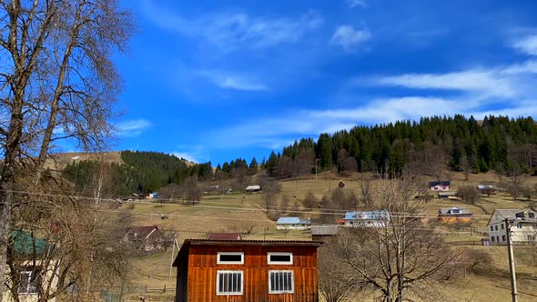 Sky timelapse with green hill and houses.