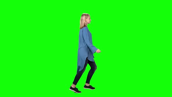 Blonde Teenager Girl Is Running with Smile at Green Screen. Chroma Key. Profile View. Slow Motion