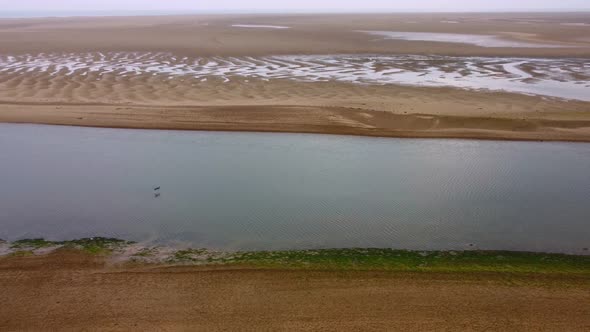 Drone Shot of Water Stream and Sand with Bird Flying Across Norfolk