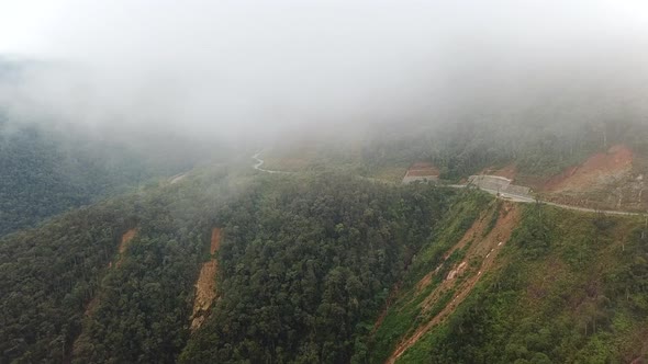 Winding Mountain Road near Misty Rainforest Trees, Drone View.