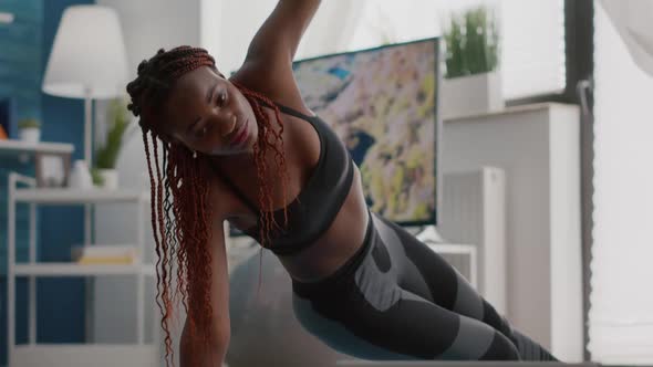 Athlete Black Woman Training on Yoga Map in Living Room Standing in Side Plank