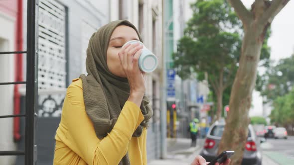 Woman wearing hijab drinking a takeaway coffee