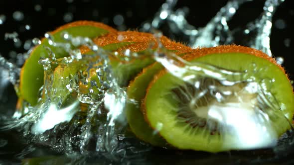 Super Slow Motion Shot of Falling And Splashing Kiwi Slice Isolated on Black Background at 1000Fps