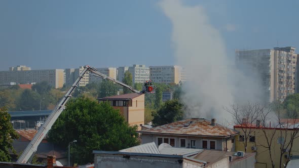 House Burning in City Neighbourhood and Firefighters Helping