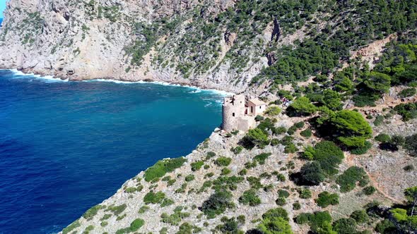 Tower of Basset Cove in Mallorca Spain with tourists exploring and admiring blue waters below, Aeria