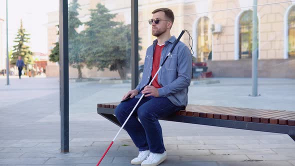 Blind Young Man Sitting at a Stop Bus