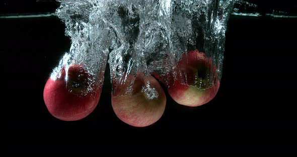 Apples, malus domestica, Fruits entering Water against Black Background, Slow Motion 4K