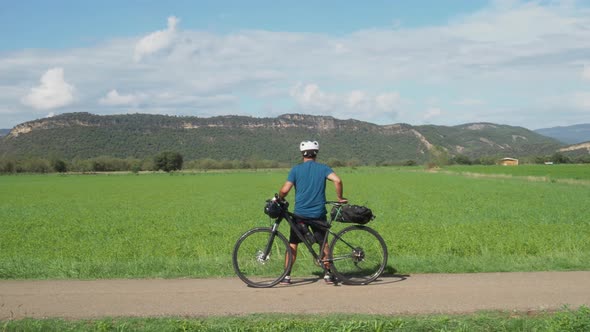 Unrecognizable Man Traveler with a Bicycle Looking at the Mountains