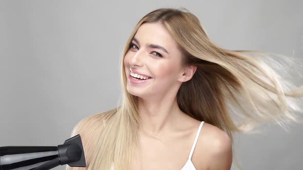 Lovely Female with Luxury Long Blonde Hair Drying It Up with Dryer