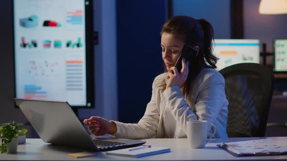 Woman Employee Speaking at Phone While Working at Laptop