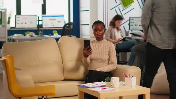 Tired Black Woman Talking with Colleague Using Video Call Holding Smartphone