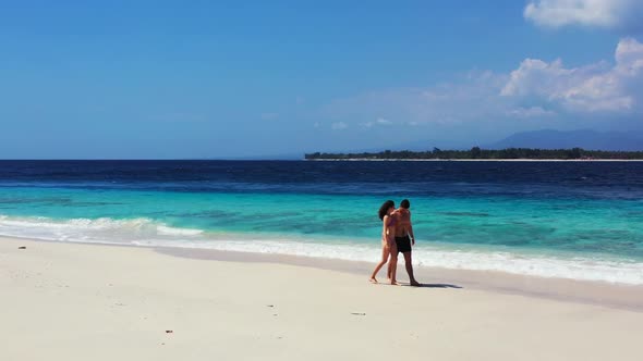 Man and woman tan on perfect seashore beach lifestyle by blue green sea with white sand background o