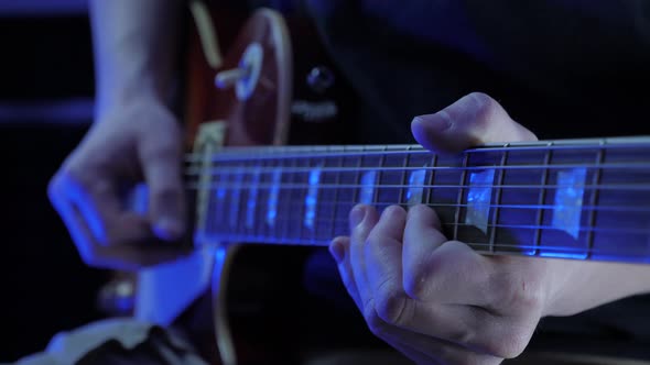 Guitarist playing on electric guitar, recording rock pop song at recording studio.