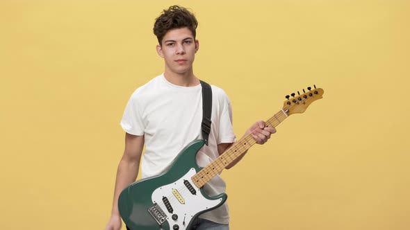 Portrait of Popular Teen Guitar Man in Casual Tshirt Using Electric Instrument at Gig Isolated Over