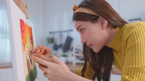 Asian young talented woman artist coloring on painting board in house.