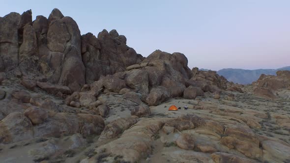 Aerial shot of a young man backpacker camping with his dog in a mountainous desert