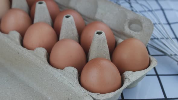 Woman hand pick up fresh chicken eggs from an egg tray.