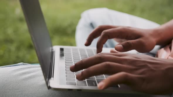 Closeup of a Dar Skinned Male Hands Working on a Laptop Outdoor