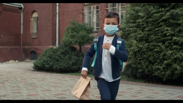 Boy Wearing Protective Medical Mask on His Face Walking Hoppingly and Looking To Camera. Kid in