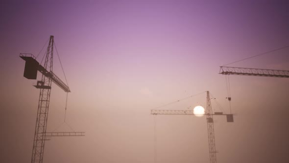 Construction Cranes In The Sunset Scene With The Passing Of A Plane 2 alt