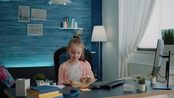 Caucasian Girl Reading Book at Desk for Primary School Work