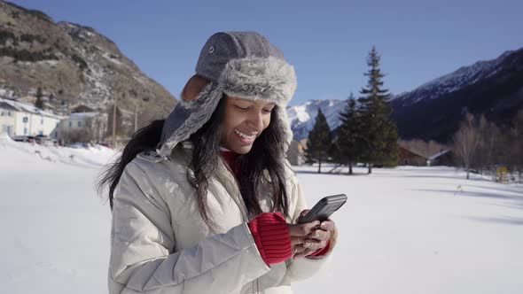 Latina Woman Using Phone in Winter Forest with Snowy Landscape