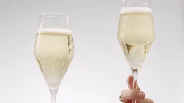 Two Glasses of Champagne Approach and Collide in Slow Motion on White Background