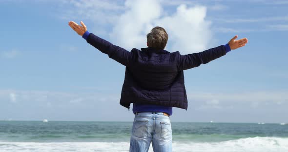 Mature man standing with arms outstretched on the beach