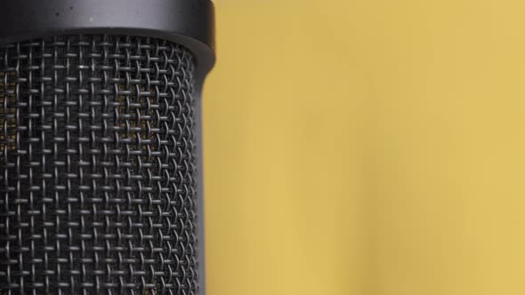 Studio Condenser Microphone Rotates on Yellow Background with Place for Text