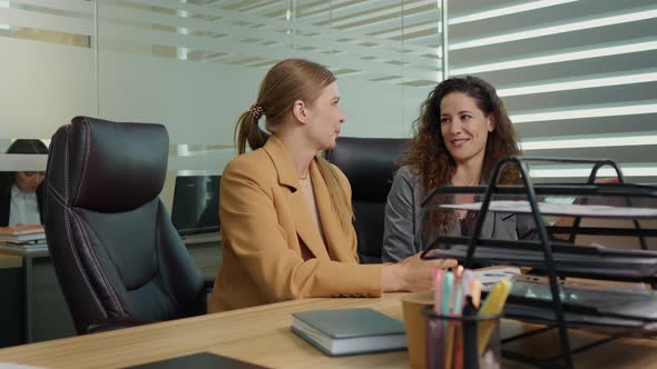 Two business ladies sharing news about best sold product in their firms.