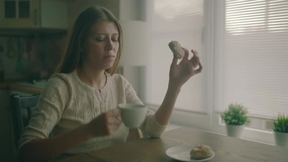 Woman Sitting At A Table Next To A Large Window At Home