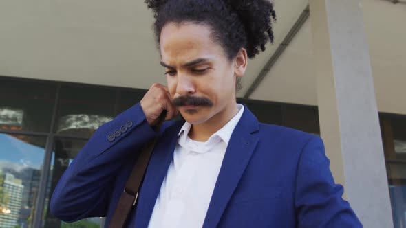 Mixed race man with moustache walking on the street and using smartphone