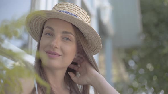 Close-up Face of Pretty Young Woman in Straw Hat Looking at the Camera Smiling Happily Outdoors