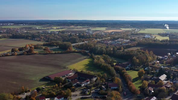 Smooth backward flight over a bavarian town in the fall season, idyllic living next to autumnal colo