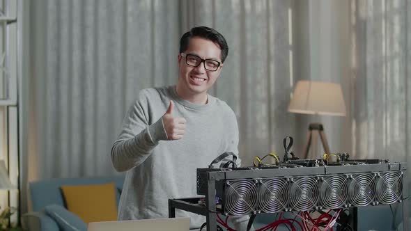 Smiling Asian Man Showing Thumbs Up Gesture While Using Laptop With Mining Cryptocurrency