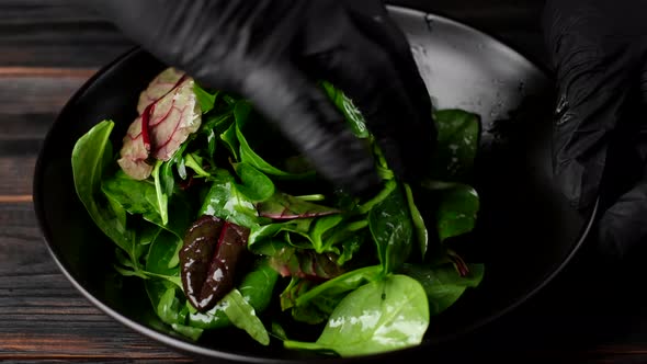 chef hands mixing green salad with arugula, spinach, olive oil. healthy lifestyle concept 