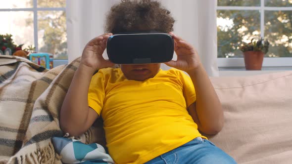 African Toddler Boy in Virtual Reality Headset Playing Video Game at Home