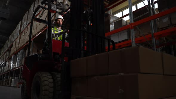 Warehouse Worker on Forklift Moving Goods in Boxes