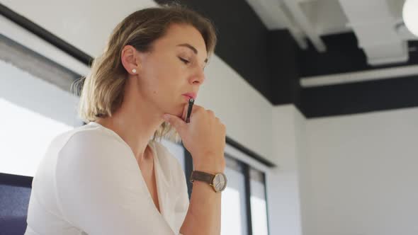 Caucasian businesswoman sitting on chair, thinking and writing