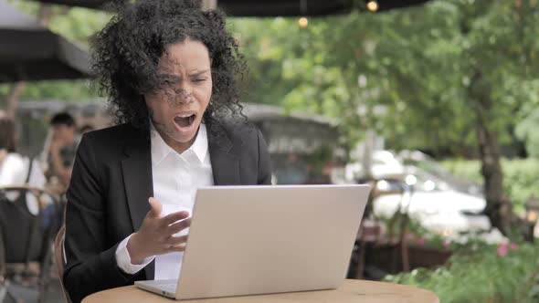 African Woman Upset By Loss Sitting in Outdoor Cafe
